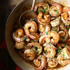 a pan filled with cooked shrimp and garnished with parsley