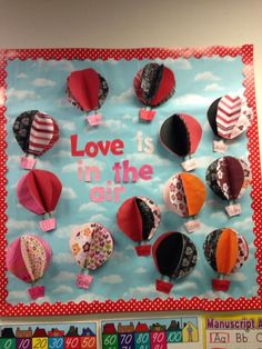 a bulletin board with lots of hot air balloons and the words love is in the air