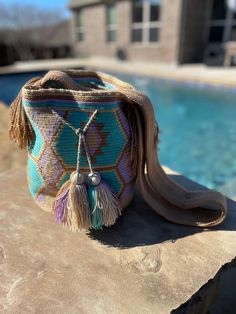 a purse sitting on top of a rock next to a swimming pool