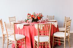 the table is set with pink and white linens, gold chairs, and floral centerpieces