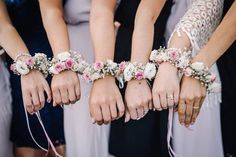 four bridesmaids hold their hands together with bracelets on each hand and flowers in the middle