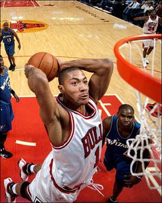 the basketball player is trying to dunk the ball into the hoop while other players look on