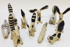 several small ceramic animals sitting next to each other on a white table top with black and white stripes