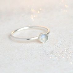 A pretty, petite, rainbow moonstone looks radiant in sterling silver. Rainbow moonstone is a translucent and pearly with hints of blue, grey, purple, pink and various colors of the rainbow as the stone catches light. Beautiful and minimalist, your moonstone ring will compliment any mood and style.  Additional stacking bands set sold separately (see last photo for styling ideas). Moonstone represents passion, intuition, success, inspiration and appealing to the emotional self, and inner discovery Minimalist Sterling Silver Birthstone Ring, Delicate White Moonstone Ring In Sterling Silver, Dainty Solitaire Moonstone Ring, Minimalist White Moonstone Ring In Sterling Silver, Dainty Moonstone Ring For Everyday, Dainty White Moonstone Ring, Everyday Moonstone Birthstone Ring, Everyday Minimalist Moonstone Birthstone Ring, Dainty Stackable Moonstone Ring