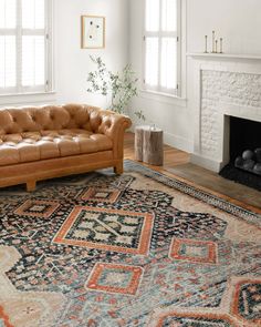 a living room filled with furniture and a rug on top of a hard wood floor