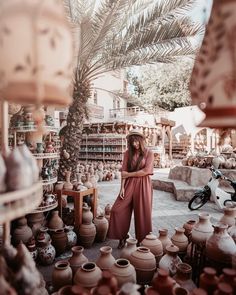 a woman standing in front of lots of vases