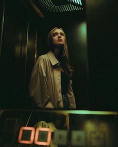 a woman standing in front of a mirror with her head turned to the side, wearing a shirt and tie