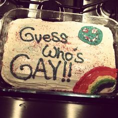 a cake with white frosting that says guess who's gay on it and a rainbow in the middle