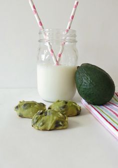 some cookies and milk on a table with two straws in a jar, one is avocado