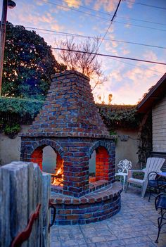 an outdoor brick pizza oven sitting on top of a patio next to a fire pit