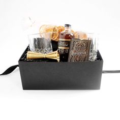 a black box filled with bottles and glasses next to an orange slice on top of a table