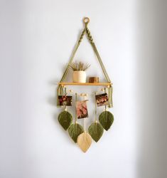 a wall hanging with pictures and plants on it's sides, attached to a white wall