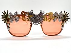 💛Unisex rose gold statement sunglasses by Alexis Exclusive. 💛These unique glasses will add that special touch to your summer / festival / holiday outfits... Be the one and only person in this unique design. 💛The frames are oversized and they have tinted rose gold/orange lenses. All along the top they have been designed in a mixture of funky jewels, embellishments and trinkets. 💛A medium weight design that are comfortable to wear. 💛Great for festivals, weddings, holidays, burning man or ever Spring Party Sunglasses With Metal Frame, Chic Metal Sunglasses For Party, Party Sunglasses With Metal Frame And Glass, Metal Frame Sunglasses For Summer, Trendy Metal Sunglasses For Festivals, Silver Sunglasses For Summer Evenings, Summer Metal Frame Sunglasses, Rose Gold Trendy Sunglasses For Summer, Gold Metal Sunglasses For Party