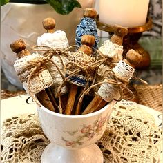 a white cup filled with cinnamon sticks on top of a doily covered tablecloth