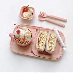 a pink tray with two sandwiches and fruit on it