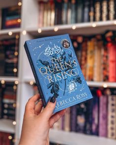 the queen's rising book is held up in front of a bookshelf