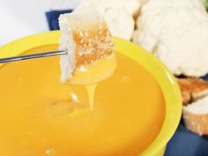 a yellow bowl filled with soup next to bread