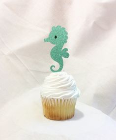 a cupcake with frosting and a green seahorse on it's top