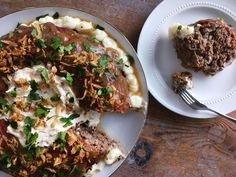 a white plate topped with meat and mashed potatoes next to a piece of meat covered in gravy