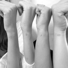 two girls with matching tattoos on their arms holding hands up to each other and looking at the camera