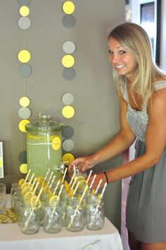 a woman standing in front of a table filled with lemonade