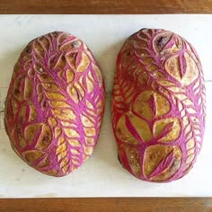 two decorative rocks sitting on top of a wooden table covered in pink and gold paint