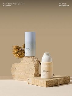 two bottles of skin care sitting on top of a piece of wood next to each other