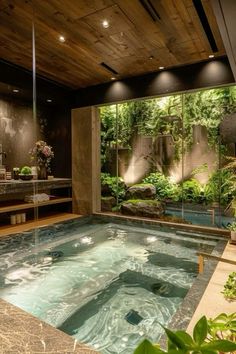 an indoor hot tub in the middle of a room with large windows and plants around it