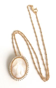 "Virgen la Milagrosa Necklace This eye-catching 1mm 18k gold plated Saturn chain hangs a gorgeous mother of pearl carved oval shape Miraculous Virgin Mary image with luminous clear cubic zirconia stones around it. This necklace is designed to be worn all day. Would be a perfect bride accessory, a gift for your wife, mother, sister, grandmother or as a gift for yourself. DETAILS: Necklace length: 17.5\" inches / 45 cm Pendant diameter: 0.9\"x \"1 inches / 2 x 2.5 cm Other Miraculous Medals are av Perfect Bride, Bride Accessories, Miraculous Medal, Beaded Accessories, Jewelry Cleaner, Virgin Mary, Necklace Length, Pearl Jewelry, Oval Shape