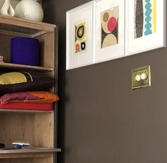 a book shelf with pictures on it next to a vase and other items in a room