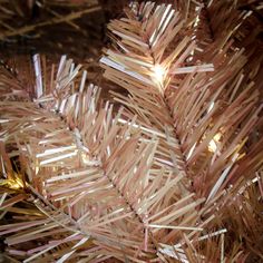 a close up view of the branches of a christmas tree that has been decorated with pink and gold strips