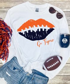 Support your favorite team in style with this Football Lips Graphic Tee Shirt. Our football shirt is customizable with your choice of team colors for the lips and text under the lips. This personalized football shirt is also available in a variety of styles. Choose from short sleeve, long sleeve, sweatshirt, tank top, or v neck styles. Our Comfort Colors upgrade is good for the ones of us who like a heavier weight shirt making it less see through. Our Bella Canvas option is great for the ones wh Football Spirit Shirts, Sports Shirts Ideas, Funny Football Shirts, Lips Graphic, School Shirt Designs, Football Shirt Designs, Football Team Shirts, Lips Shirt, Sports Mom Shirts