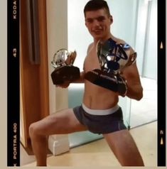 a young man is posing for a selfie with his trophy and soccer gloves in front of him