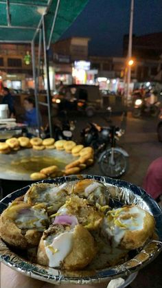 a person holding a plate with food on it in front of other plates and motorcycles