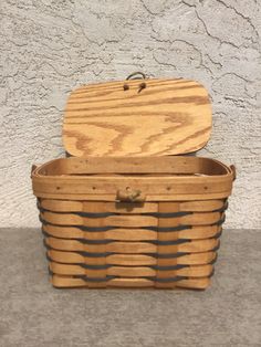 an old wooden basket sitting on top of a cement floor next to a white wall