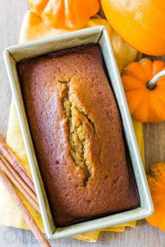 a loaf of pumpkin bread sitting on top of a table next to oranges and cinnamon sticks