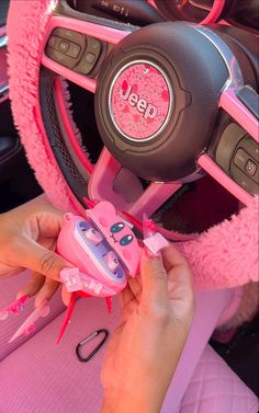 a person holding a pink toy in their hand and steering wheel with other items on it