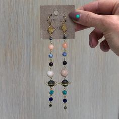 "handmade from solid brass Fishhook earring with Silicone push back closure. Earrings Hang approx. 4.5\" long. Crystal planets include: Mercury- hematite Venus- rhodonite or rhodochrosite Earth- sodalite, chrysocolla Mars- jasper Jupiter- agate Saturn - rainbow malachite, aura druzy Uranus- amazonite, howlite Neptune- howlite, quartzite Pluto - labradorite All metals used by Pop & Locket are nickel free and hypoallergenic. Steel wool works wonders for extra shine for a lifetime of wear. Each Crystal Planet, Earrings Space, Space Earrings, Planet Earrings, Gold Sun, Fish Hook Earrings, Earrings Crystal, Unique Earrings, Solar System