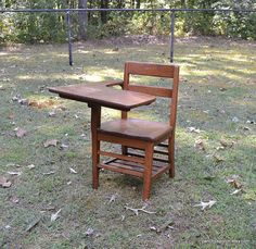 a wooden chair sitting on top of a grass covered field next to a small table