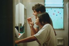 a man and woman brushing their teeth in the bathroom