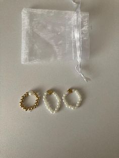 two pairs of pearl and gold hoop earrings on a white surface next to an organ bag