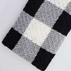 a black and white crocheted blanket with squares on the bottom is laying down