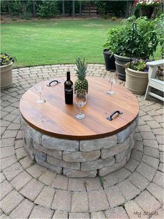 a table with two wine glasses and a pineapple on it in the middle of a brick patio