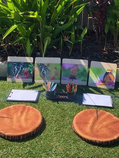 four pieces of wood sitting on top of a grass covered field next to paintings and pencils