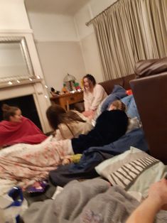 a group of people laying on top of a bed in a living room next to a fire place