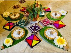 a table topped with lots of colorful plates filled with food and flowers on top of it