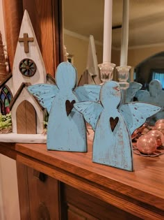 two wooden angel figurines sitting on top of a table next to a mirror