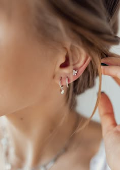 This is a set of 3 different, yet complementary earrings, all made from 925 sterling silver. It includes: ✅ 1 huggie earring with a small, solid, heart-shaped pendant attached to its lower edge, ✅ 1 huggie earring with 9 tiny clear-coloured zirconia stones set into its outer rim, and ✅ 1 tiny butterfly-shaped stud earring featuring 2 Marquise-shaped, clear-coloured zircon stones set above 2 small round, clear-coloured zircon stones. Subtle, elegant, and versatile, this set is an easy way to upda 3 Earrings, Huggie Earrings Silver, Huggie Earring, Stacked Earrings, Butterfly Earrings Stud, Butterfly Earrings, Single Earring, Ear Jewelry, Stud Earring