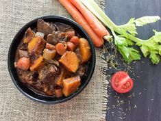 a bowl filled with stew next to carrots and celery