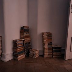 stacks of books sitting on the floor in front of a door with a clock above them